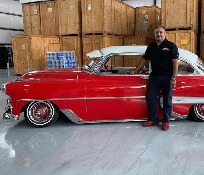 a guy in front of a red car